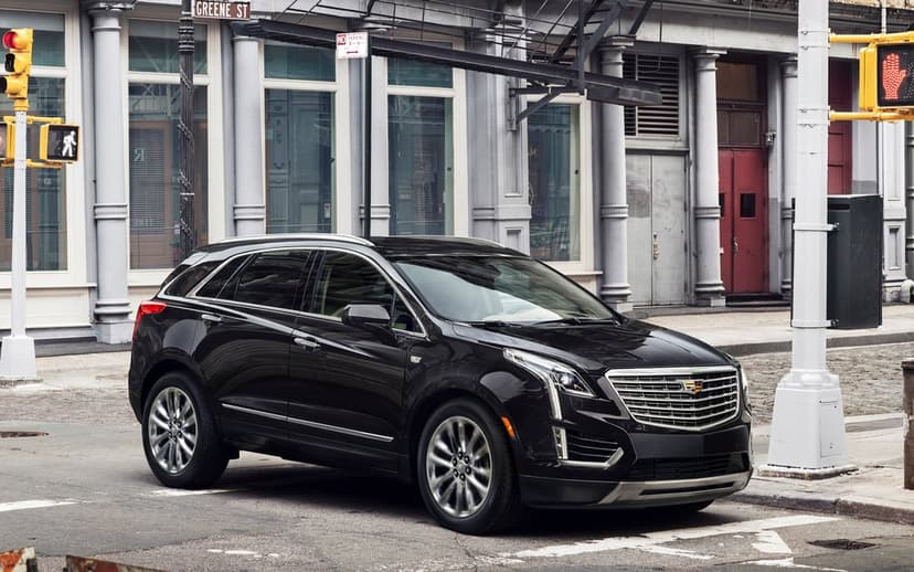 Black Cadillac XT5 luxury SUV parked on a cobblestone city street with classic architecture and Greene St sign.