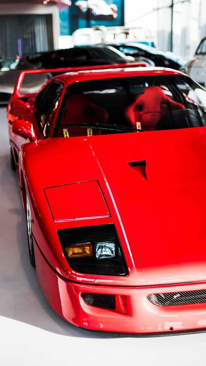 Red Ferrari F40 front bumper with air intakes, pop-up headlights, and a central hood vent under studio lighting.