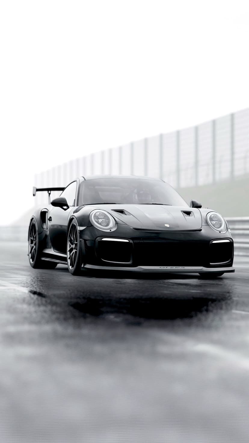 Porsche 911 GT2 RS with a massive rear wing parked on glistening wet asphalt under a dark overcast sky.