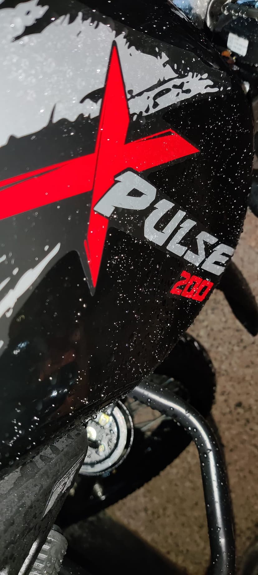 Black motorcycle side panel featuring a red X graphic and silver Pulse 200 logo with fresh water droplets.