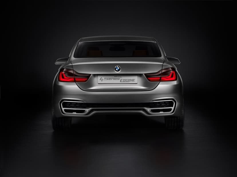 Rear of a silver BMW Concept 4 Series Coupe with glowing red L-shaped taillights on a dark black background.