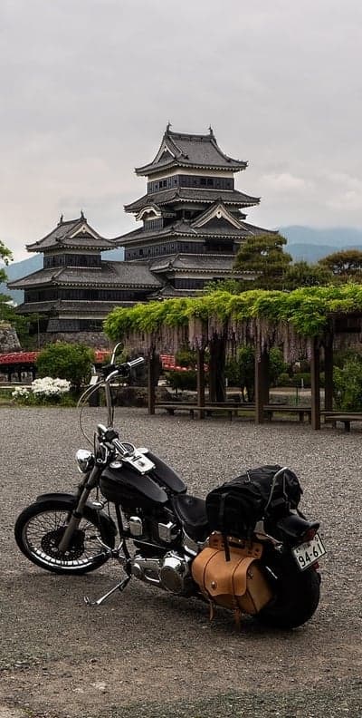 Motorcycle parked at historic Japanese castle with wisteria