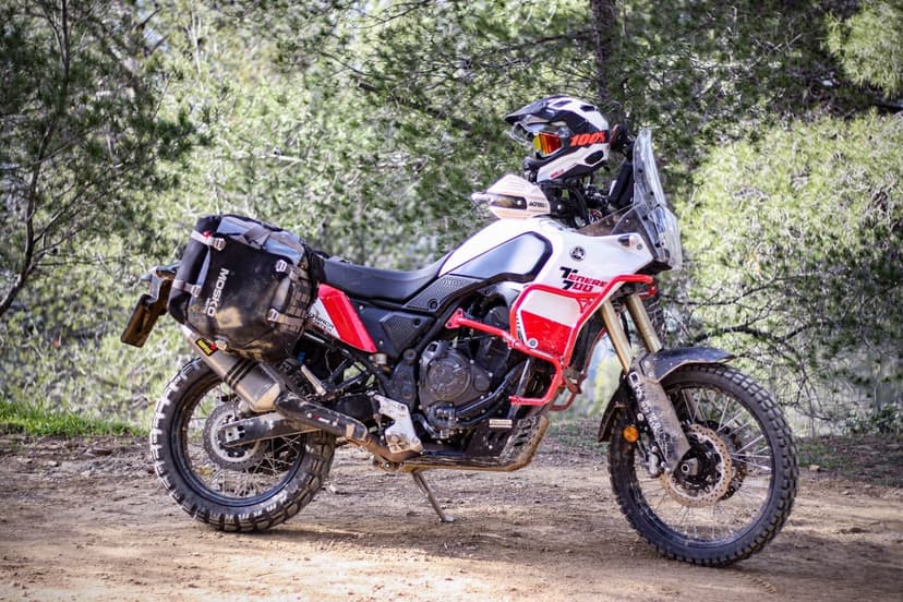 Yamaha Tenere 700 adventure motorcycle with off-road gear parked on a forest trail in daylight.