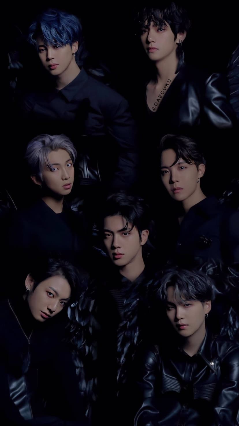 Seven BTS members stand in dark tailored clothing against a black background with somber, intense expressions.