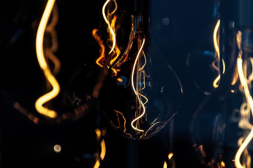 Glowing amber Edison bulb filaments in a spiral shape against a dark background in a macro photography style.