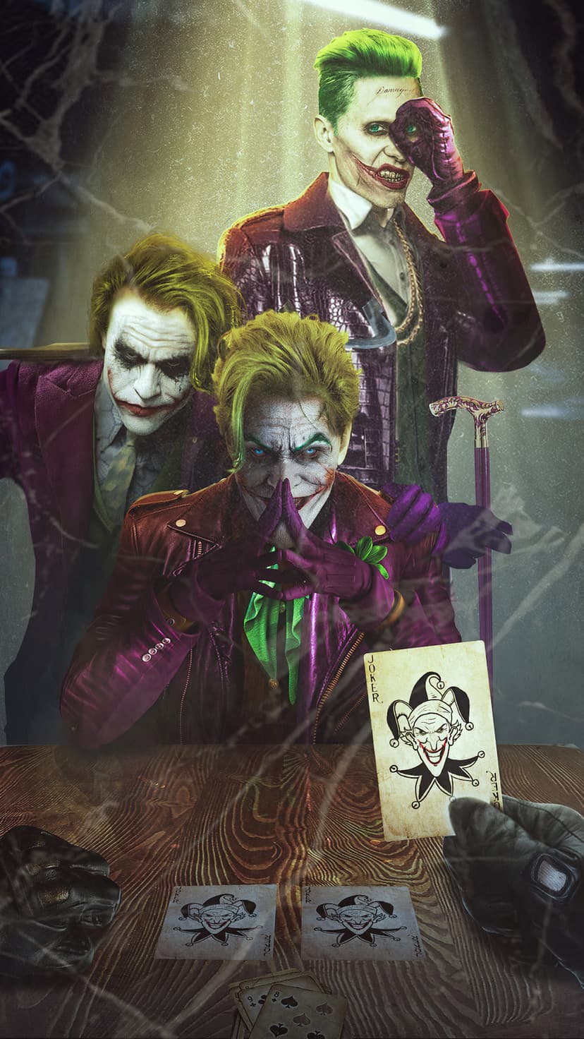 Three versions of the Joker sit at a wooden table playing cards in a dark, moody room with dramatic shadows.