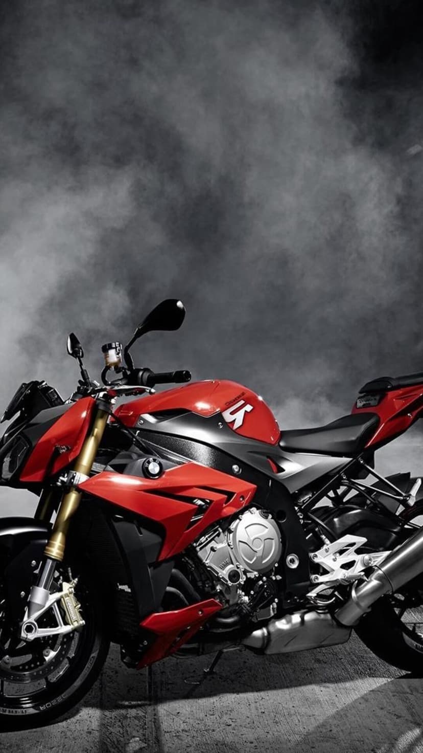 Red BMW S1000R sportbike parked within thick dark smoke, showcasing detailed engine parts and alloy wheels.