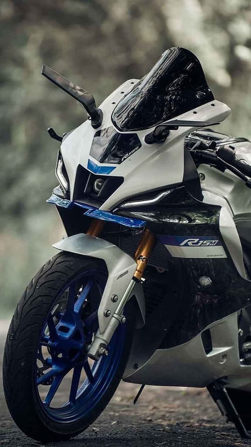 Yamaha R15 sports motorcycle in blue and white featuring a sharp front fairing and tire with a blurred background.