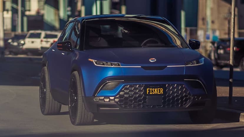 Matte blue Fisker Ocean SUV with a geometric grille parked on a cinematic sunlit city street background.