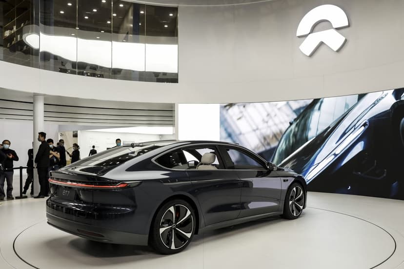 Dark NIO ET7 electric sedan on a white circular platform inside a bright, modern showroom with a brand logo.
