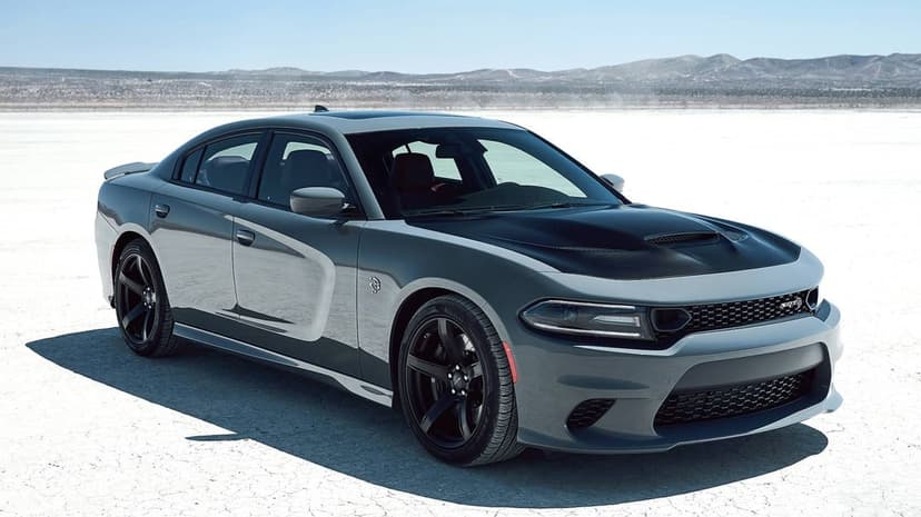 Gray Dodge Charger SRT Hellcat with a black hood parked on a cracked white salt flat under a clear sky.