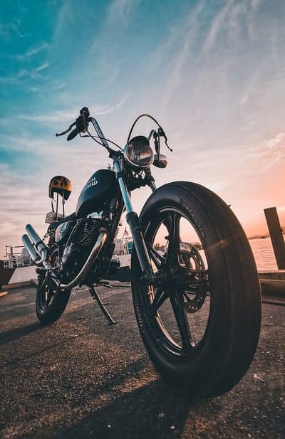 Motorcycle and Helmet by the Ocean at Sunset