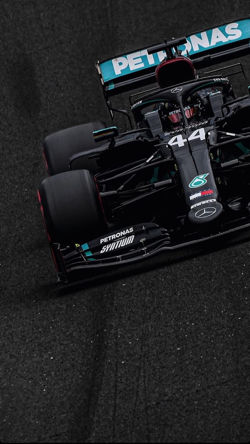 Lewis Hamilton's black and turquoise Mercedes F1 car maneuvers on a racing circuit at high speed from a low angle.