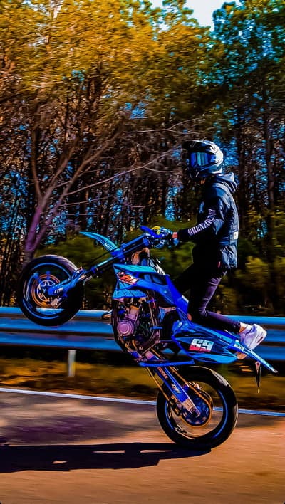 Motorcyclist Doing a Wheelie on a Blue Dirt Bike