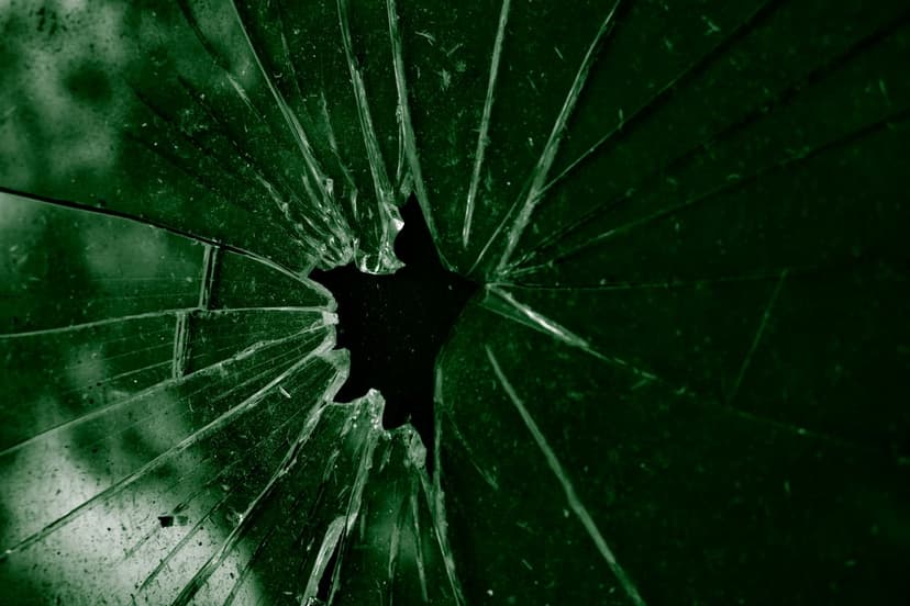 Emerald glass shards radiate from a dark star-shaped void with intricate cracks and sharp geometric fractures.