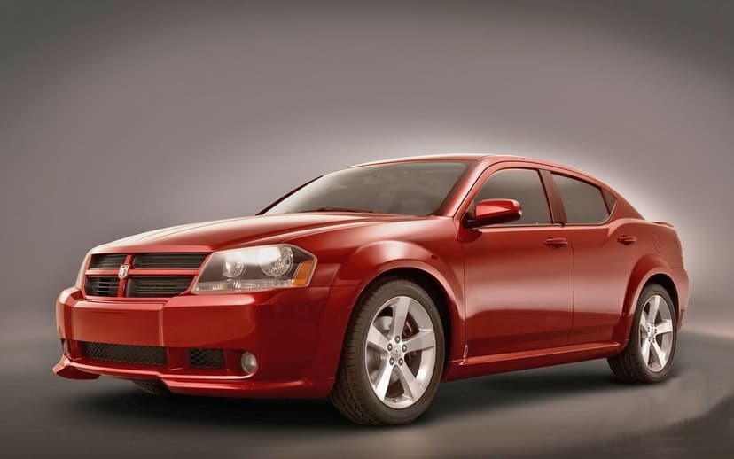 Polished red Dodge Avenger concept sedan featuring alloy wheels on a sleek neutral grey studio background.