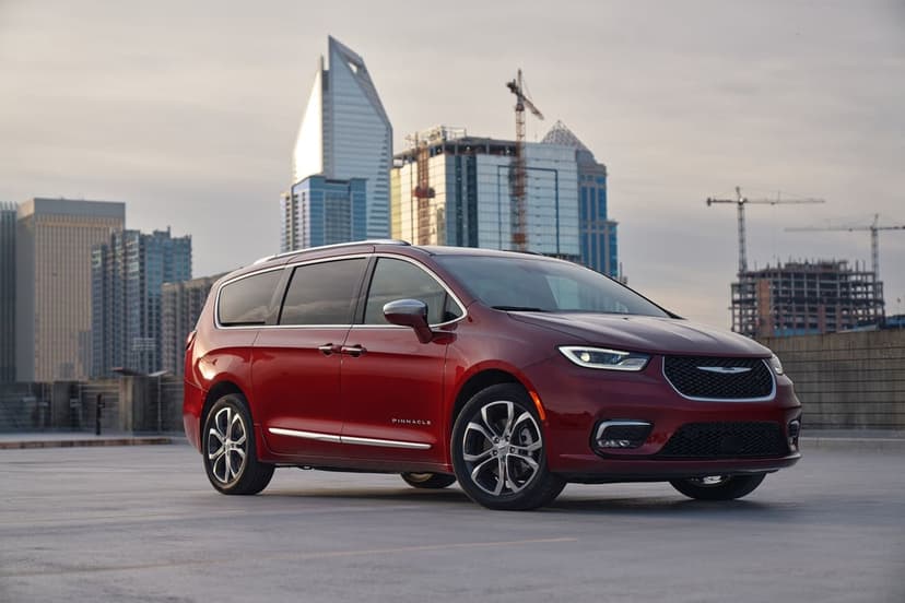 Red Chrysler Pacifica Pinnacle parked on a rooftop against a modern city skyline under a hazy sky.