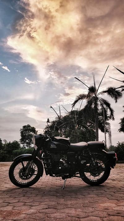 Black Royal Enfield Motorcycle Under Dramatic Sunset Sky