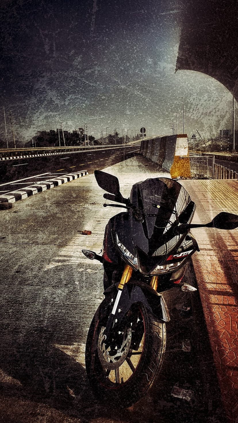Black sportbike parked on an asphalt highway shoulder under a cloudy sky with a gritty vintage filter.