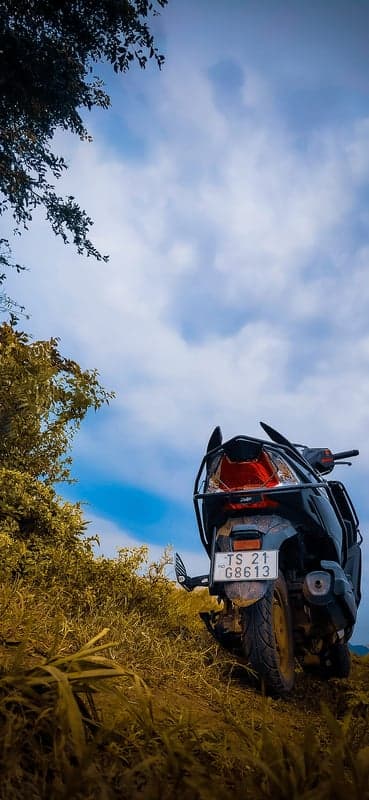 Motorcycle on a grassy hill under a cloudy sky