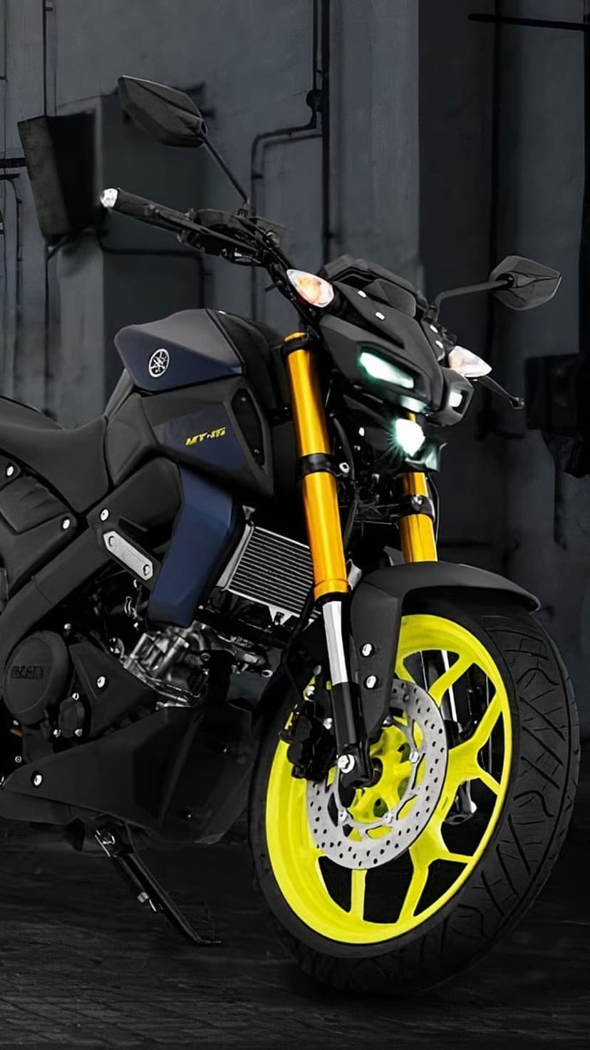 Yamaha MT-15 motorcycle with bright yellow forks and wheel rims parked in a dimly lit industrial setting.
