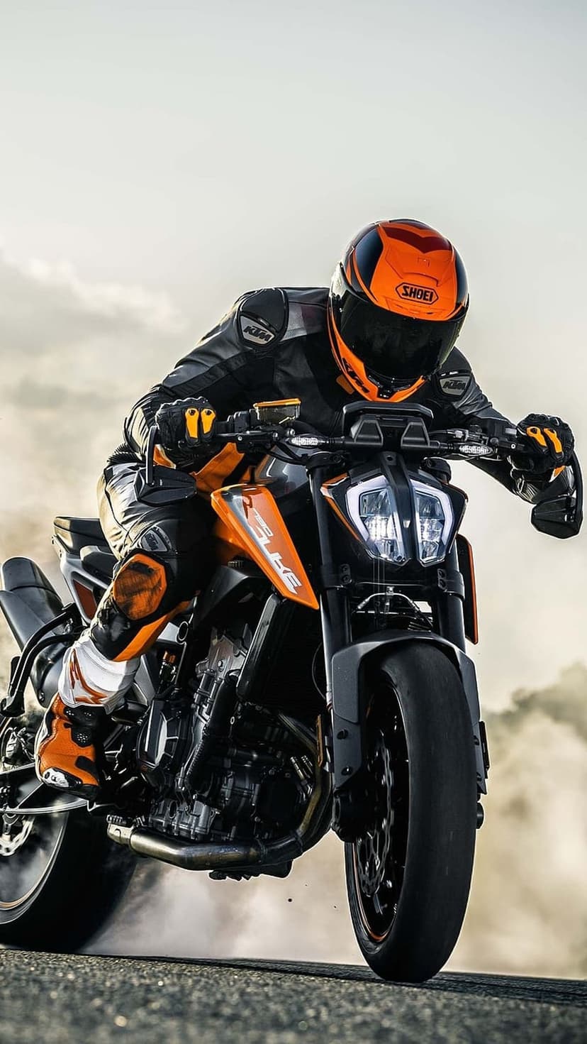 KTM rider leaning low in a sharp turn with clouds of white smoke and dust kicking up from the rear tire.