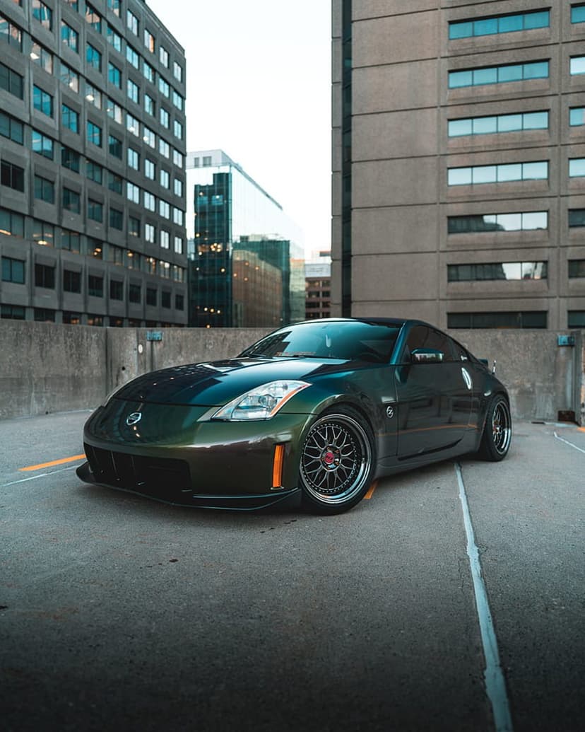 Nissan 350Z with iridescent paint and custom wheels parked near concrete buildings in an urban landscape.