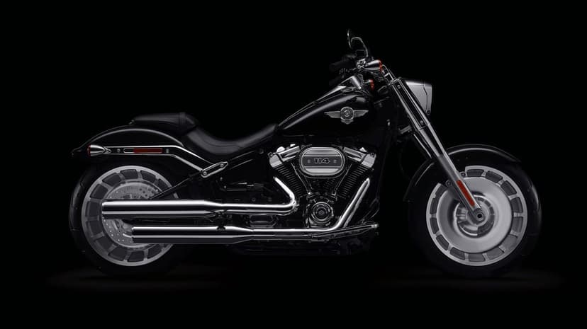 Side profile of a black Harley-Davidson Fat Boy 114 motorcycle with chrome accents on a dark background.
