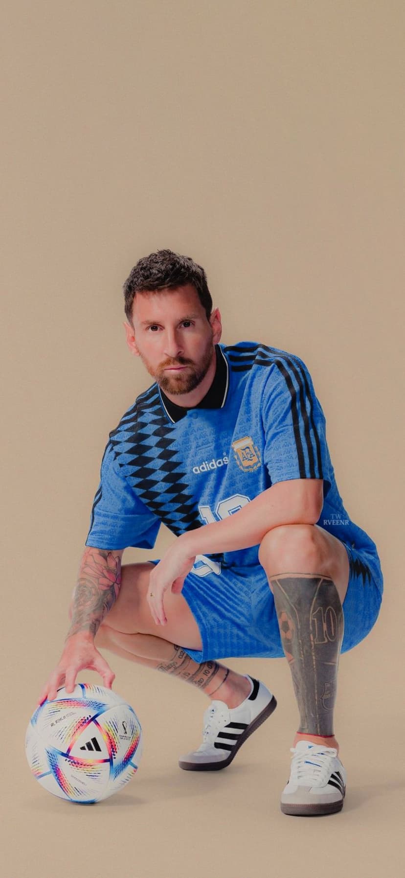 Lionel Messi in a blue Argentina jersey crouches next to a multicolored soccer ball on a warm background.