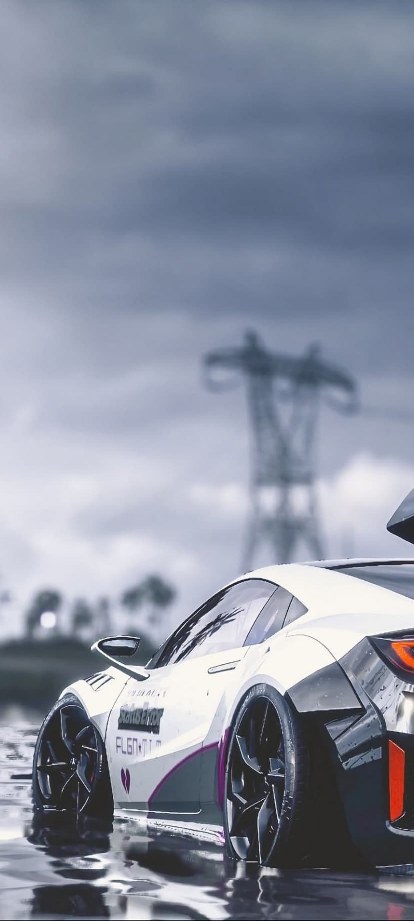 White sports car with a wide body kit sits on wet asphalt under a dark sky near a large electricity pylon.