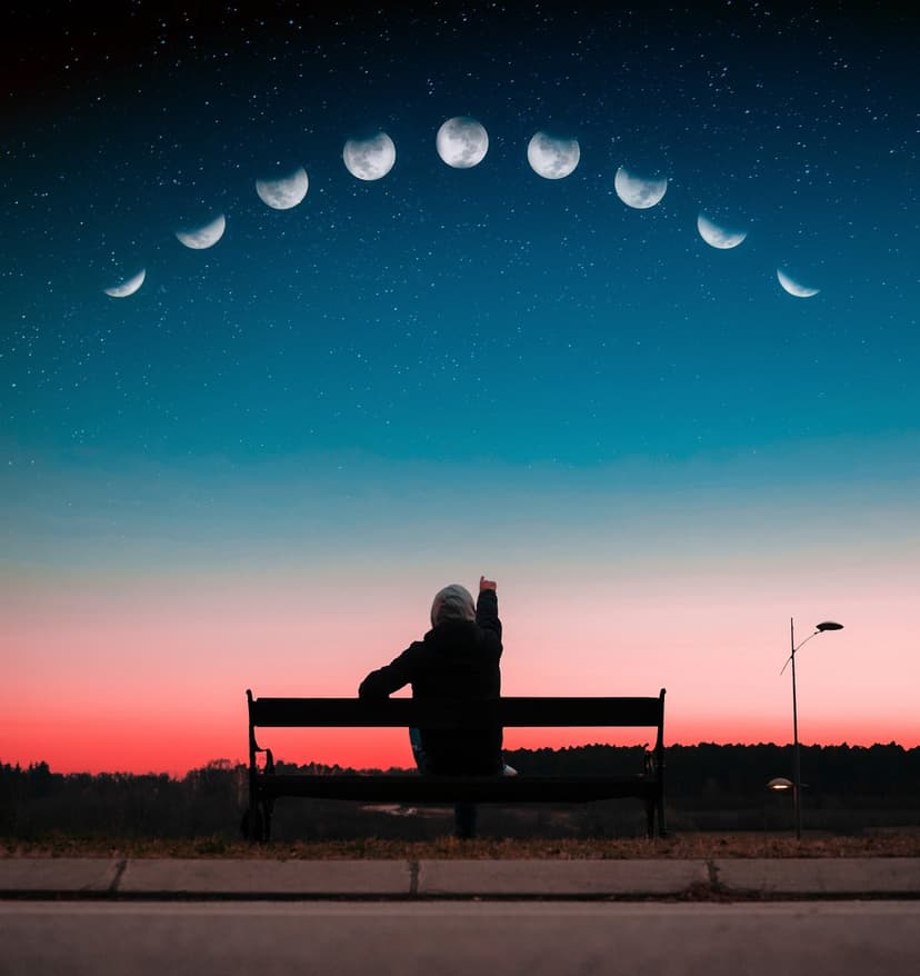 Person sitting on a park bench observing a lunar cycle arc across a sunset and starry night sky backdrop.