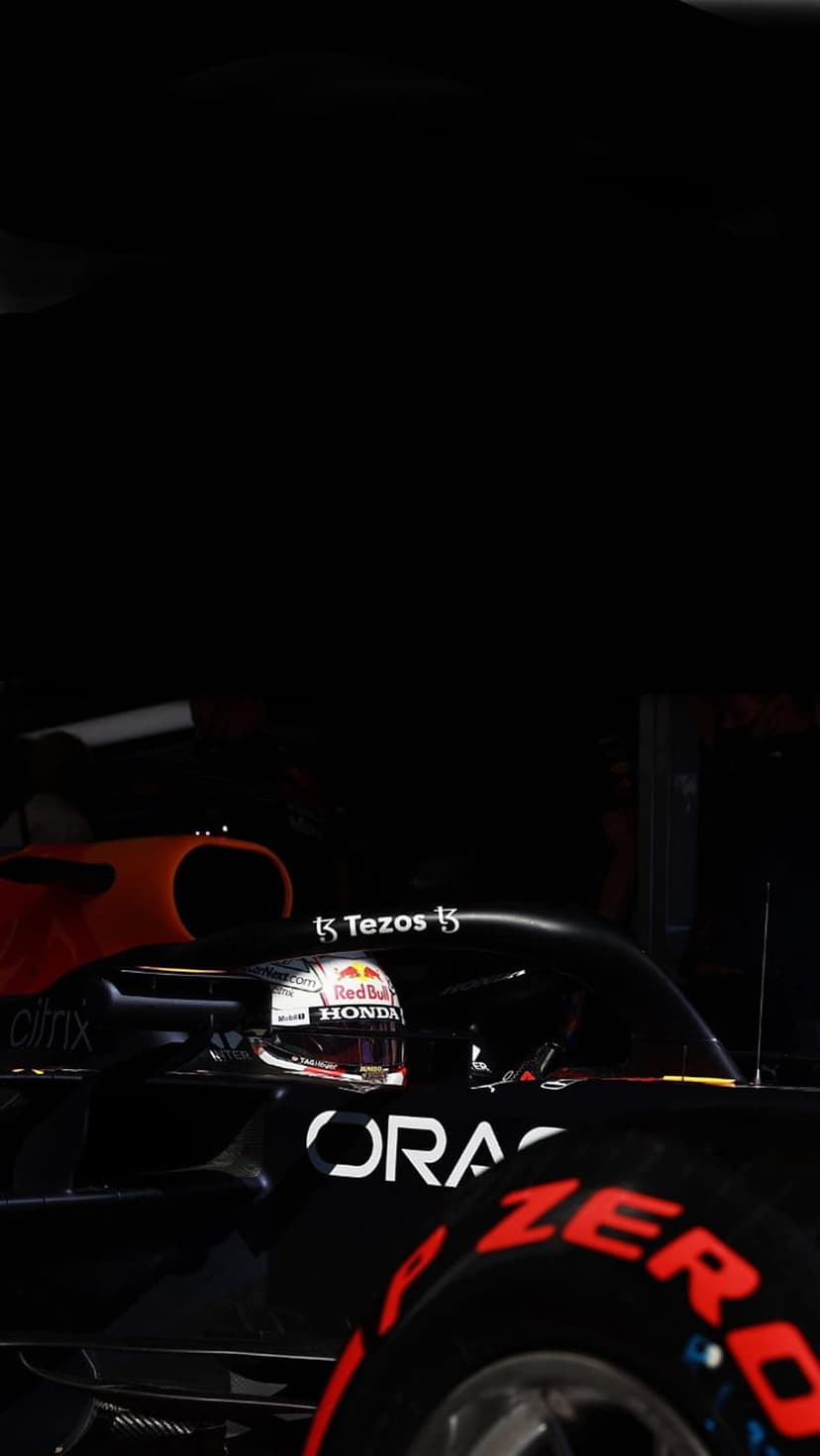 Max Verstappen wearing a racing helmet inside a Red Bull Formula 1 car cockpit with dark cinematic lighting.