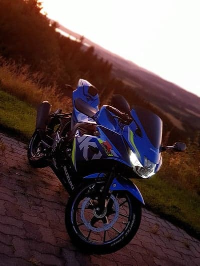Blue Suzuki Motorcycle on a Scenic Hillside at Sunset