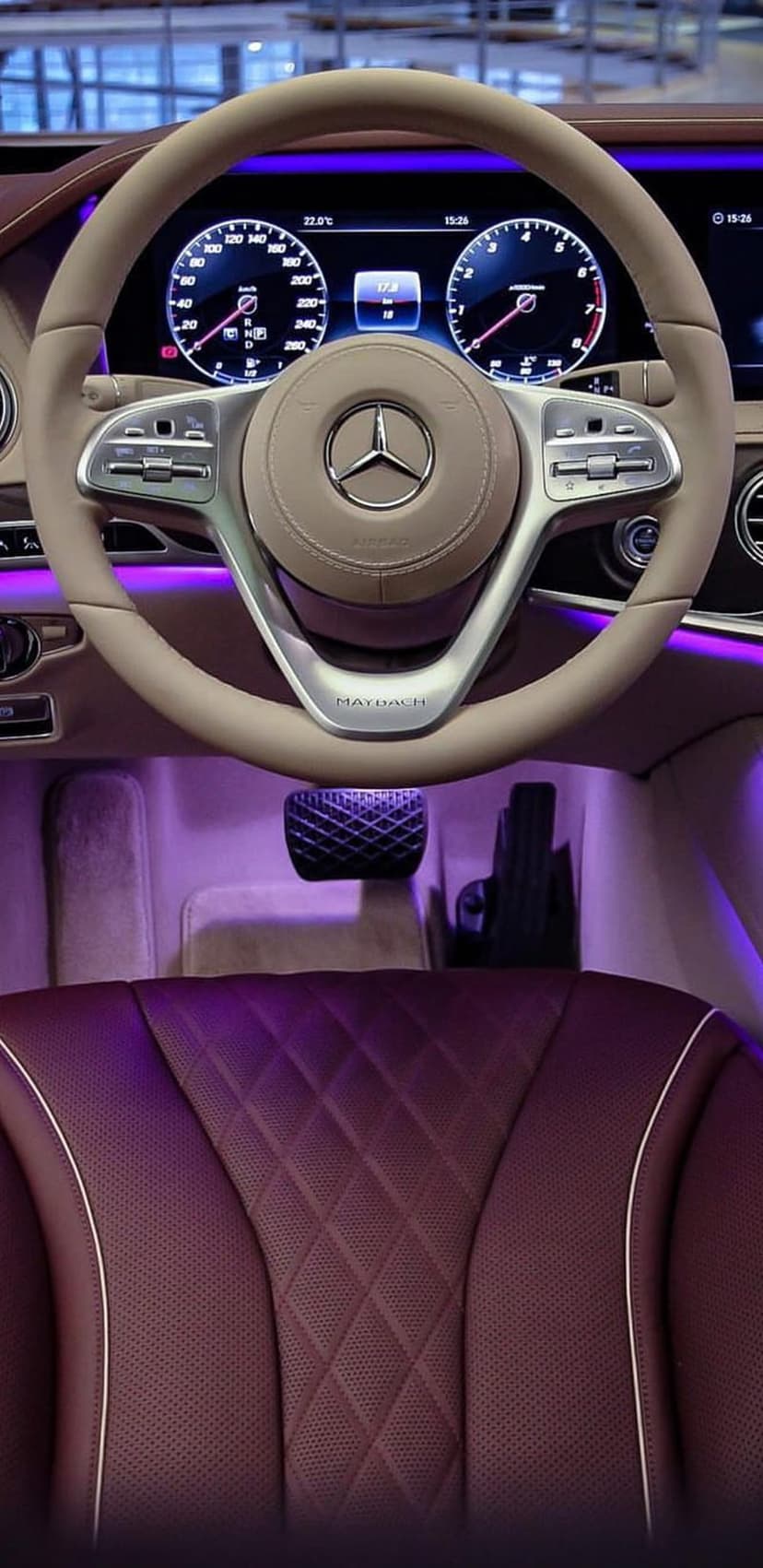 Mercedes-Maybach steering wheel and burgundy diamond-quilted leather seats glowing under purple ambient light.