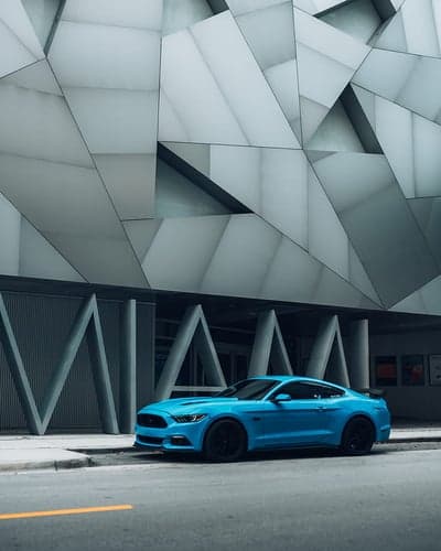 Sleek Blue Ford Mustang City Architecture Mobile Wallpaper