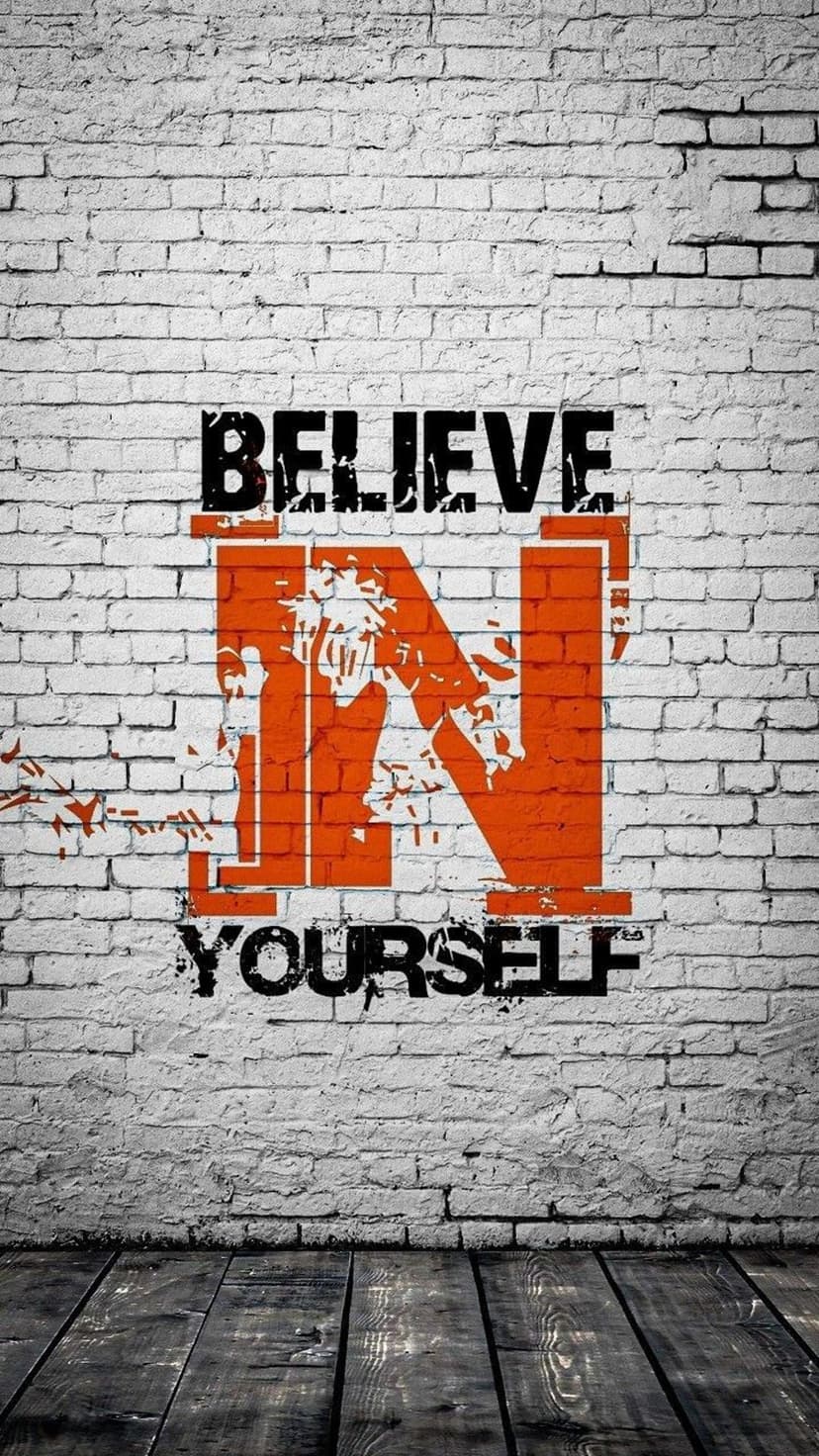 Believe in Yourself text spray painted on white brick wall with orange accents and a dark wood floor.