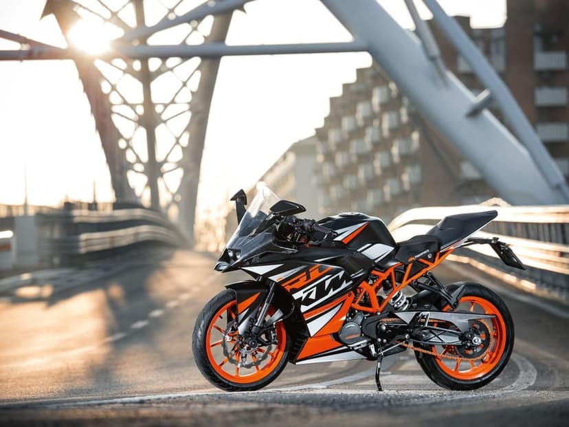 KTM RC sportbike on an urban bridge with golden hour sunlight and modern architectural steel beams.