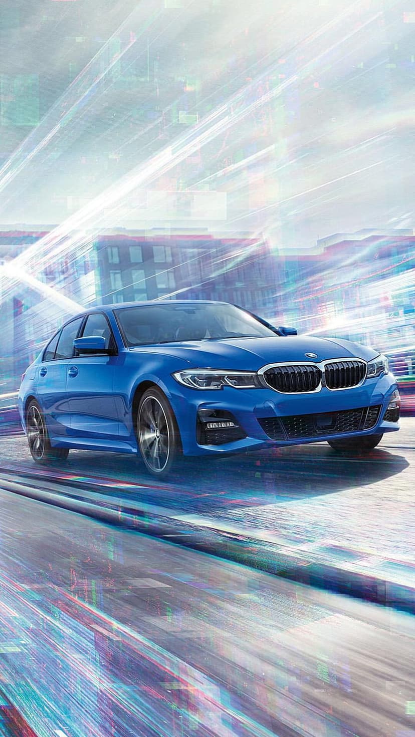 Blue BMW 3 Series sedan speeds past glowing city lights with vibrant motion blur in a vertical night shot.