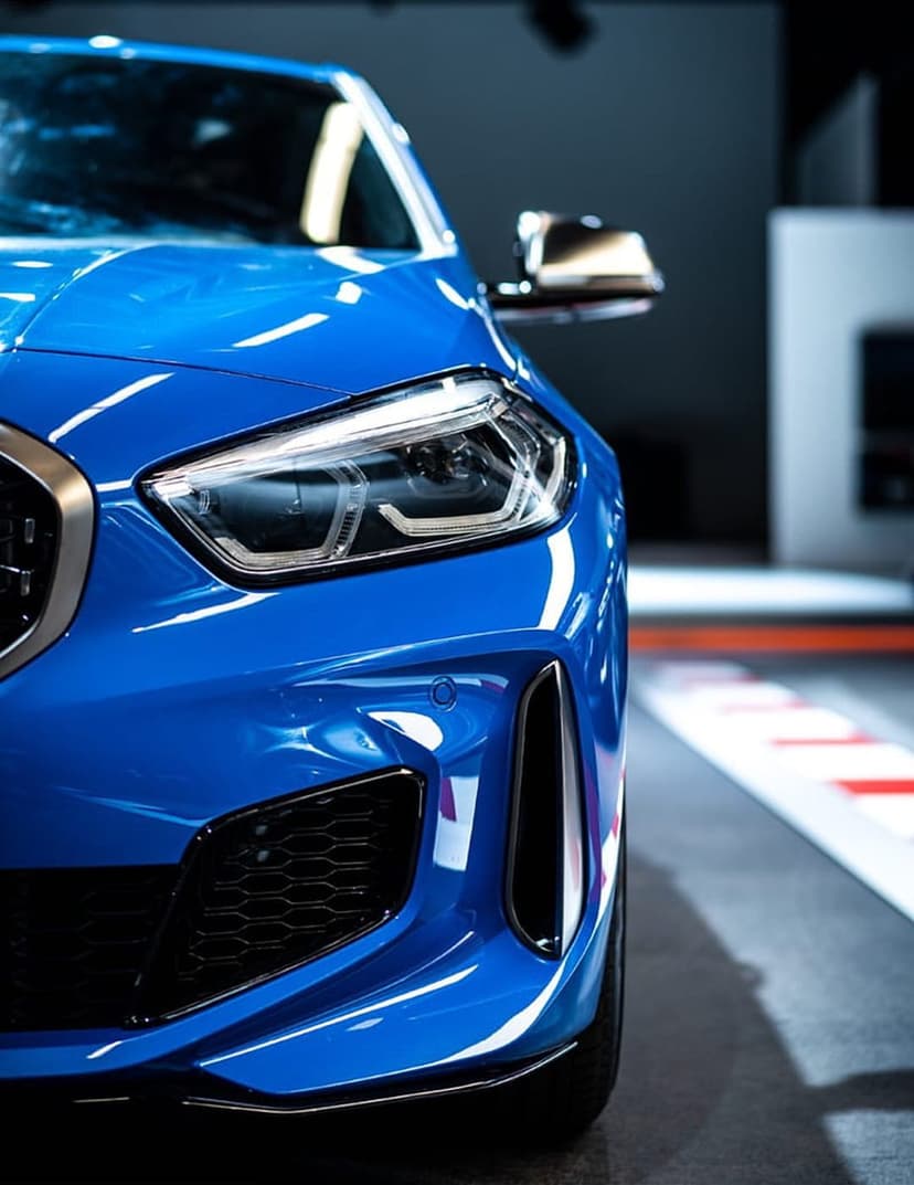 Blue BMW sports car front end showing glowing LED headlights, textured grille, and polished metallic paintwork.