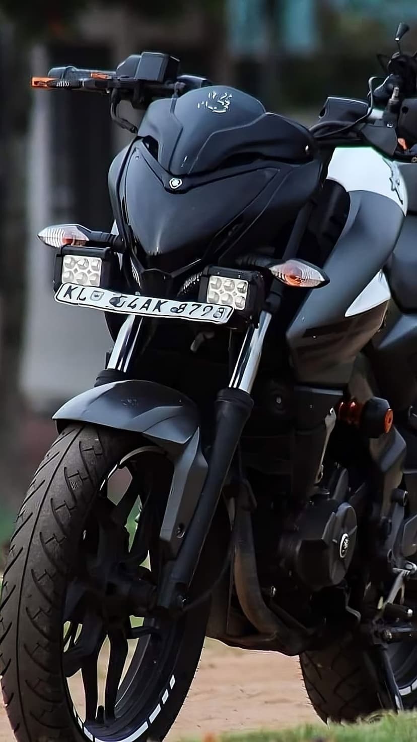 Bajaj Pulsar NS200 motorcycle with dual LED auxiliary lights and white rim stickers on a black front wheel.