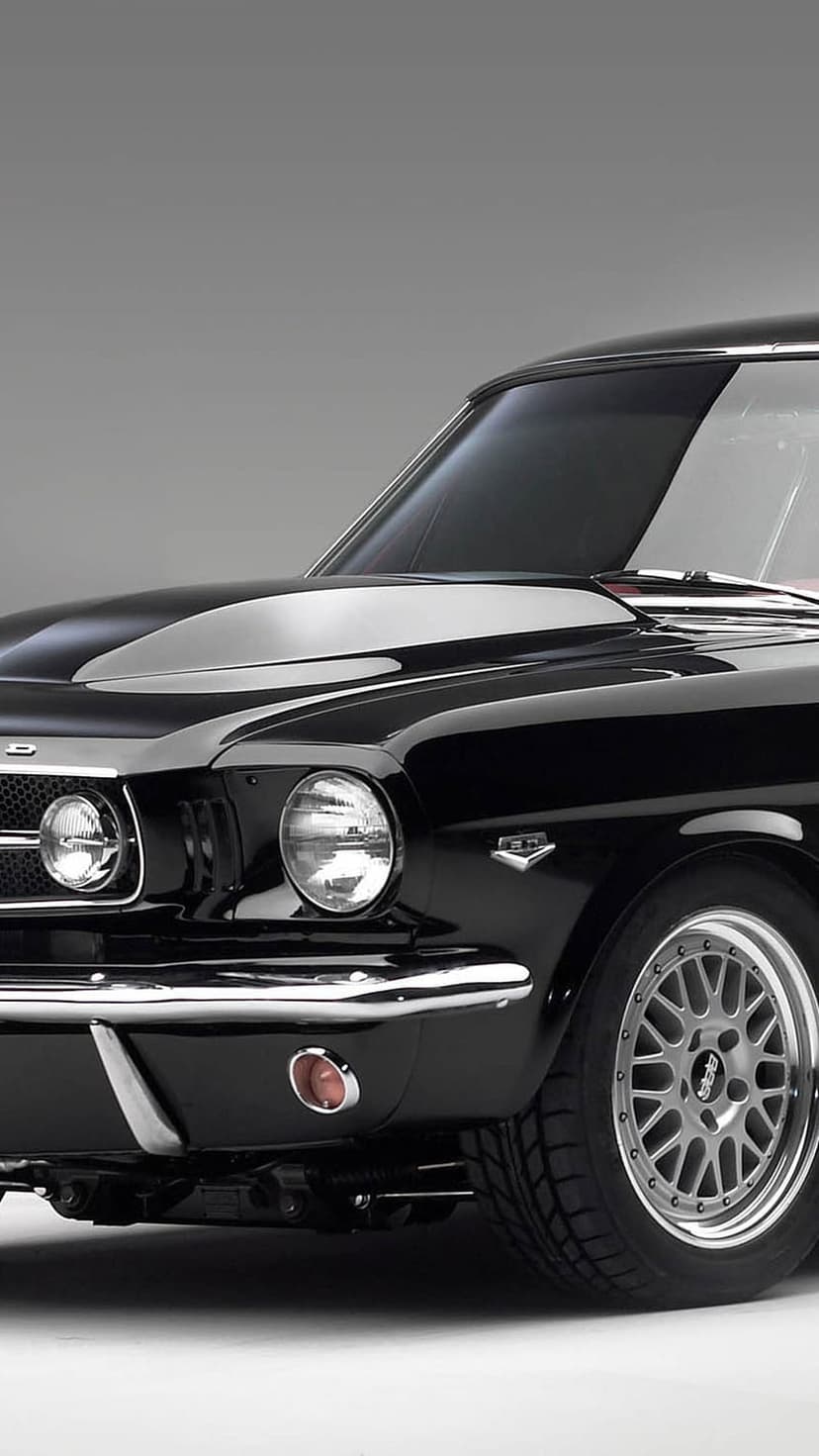 Black Ford Mustang GT front view showing a chrome grille, round headlights, and metallic hood scoop details.