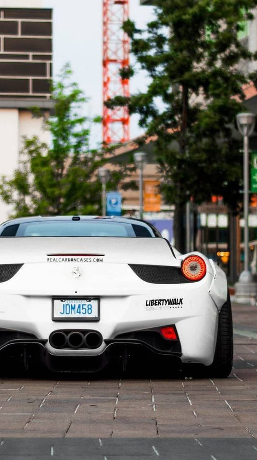 White Ferrari 458 with Liberty Walk widebody kit, quad exhausts, and a JDM license plate in an urban setting.