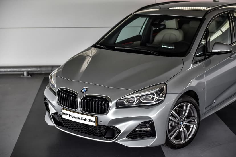 Silver BMW 2 Series Active Tourer with LED headlights and M Sport bumper in a bright studio showroom.