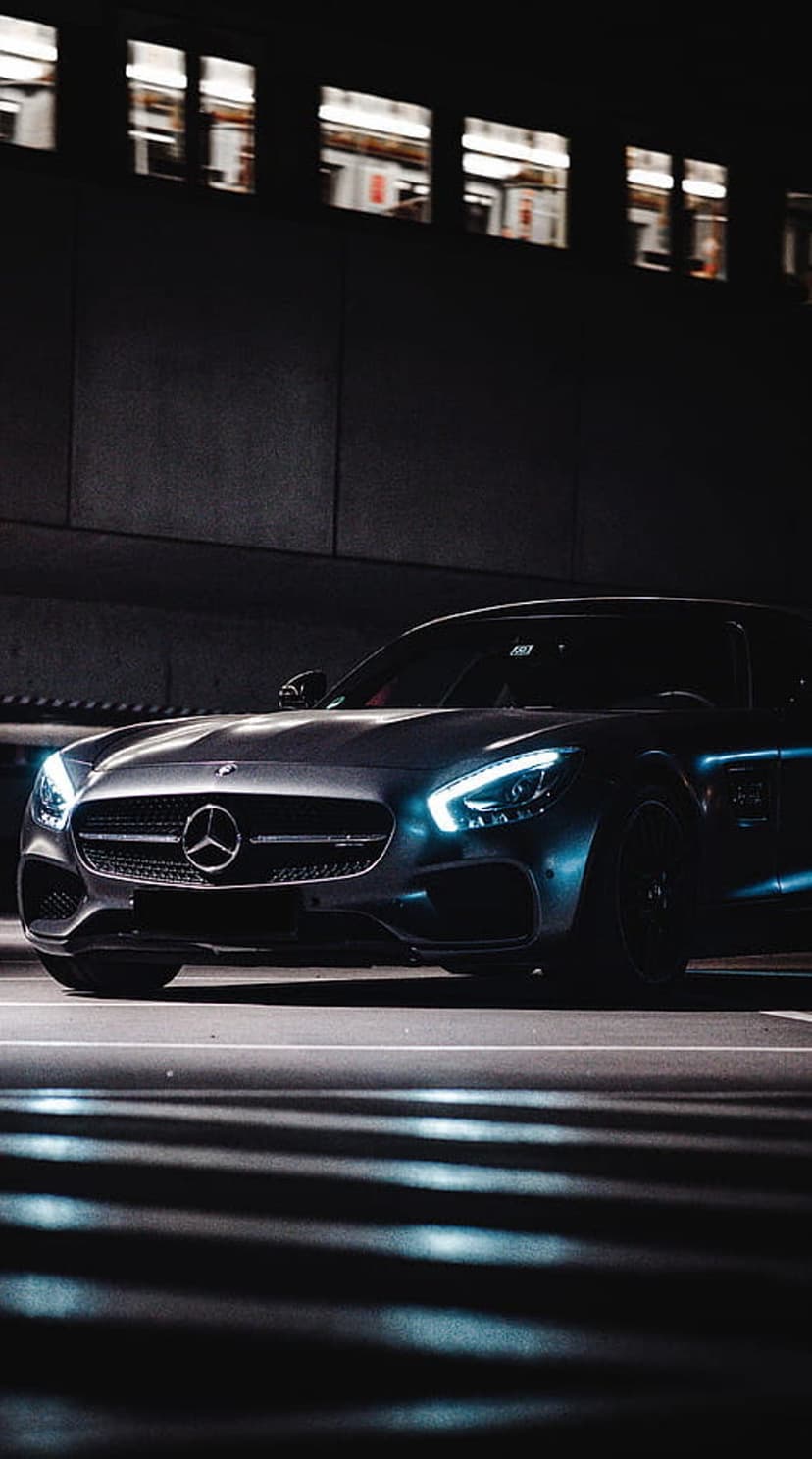 Mercedes-AMG GT S with glowing blue headlights parked on a dark urban road during a moody night photoshoot.