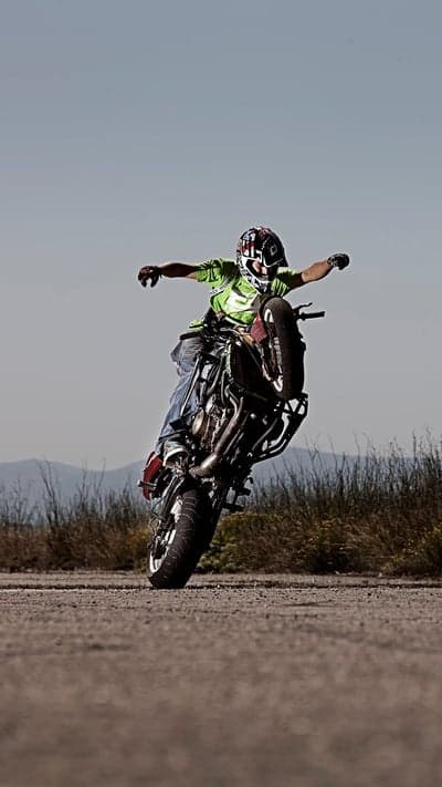 Motorcycle stunt rider performing a wheelie outdoors