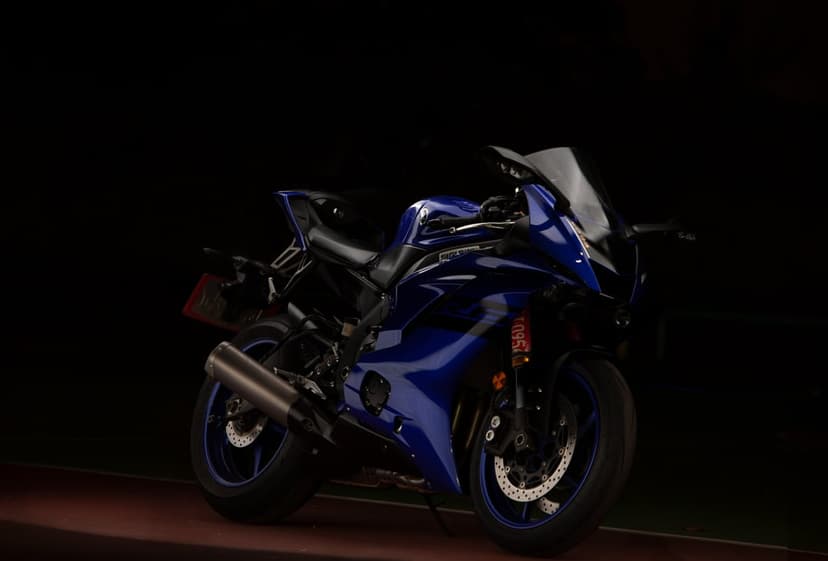 Yamaha R6 motorcycle with blue fairings and gold front forks isolated against a dark, moody background.
