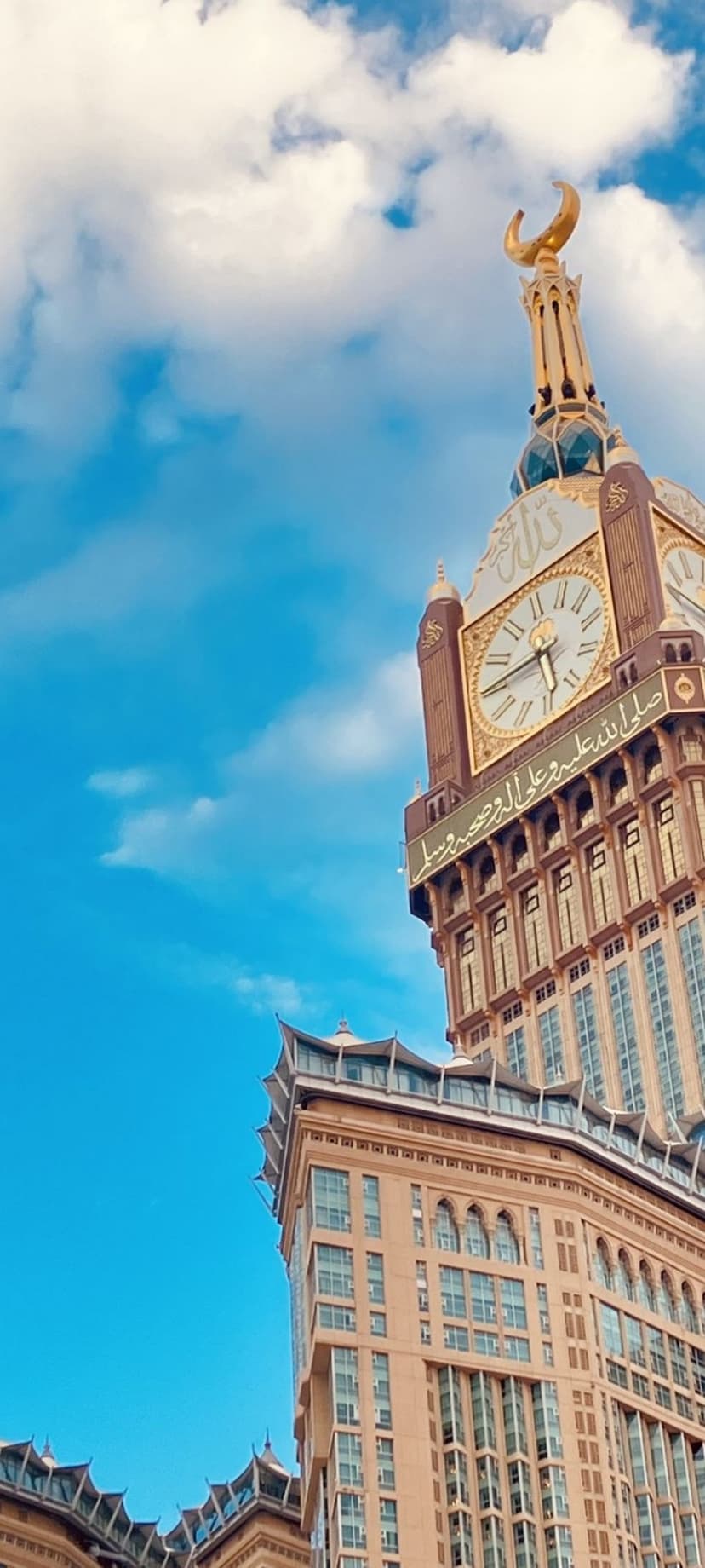 Makkah Clock Royal Tower with a golden crescent moon against a blue sky and white clouds in Saudi Arabia.