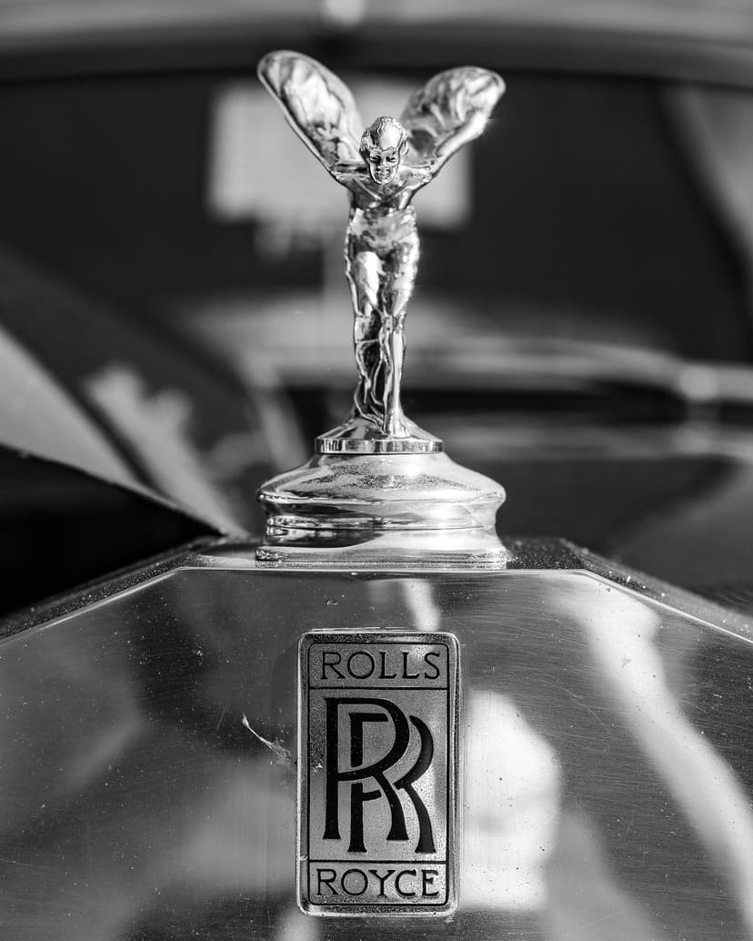 Spirit of Ecstasy hood ornament and Rolls-Royce badge feature sharp metallic details in a black and white close-up.