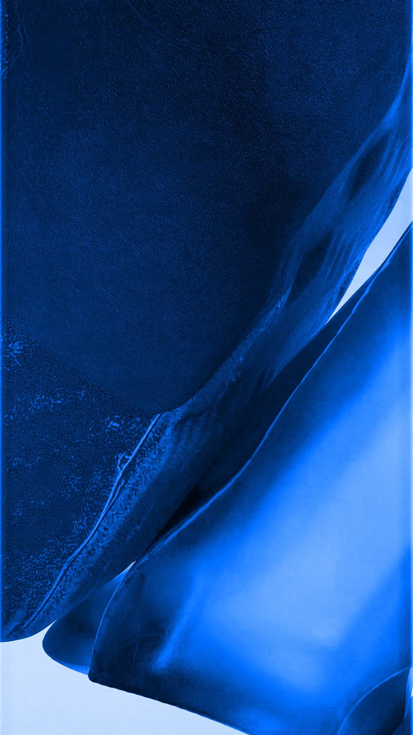Flowing waves of cobalt and navy blue fabric with alternating matte and shimmering textures in soft light.