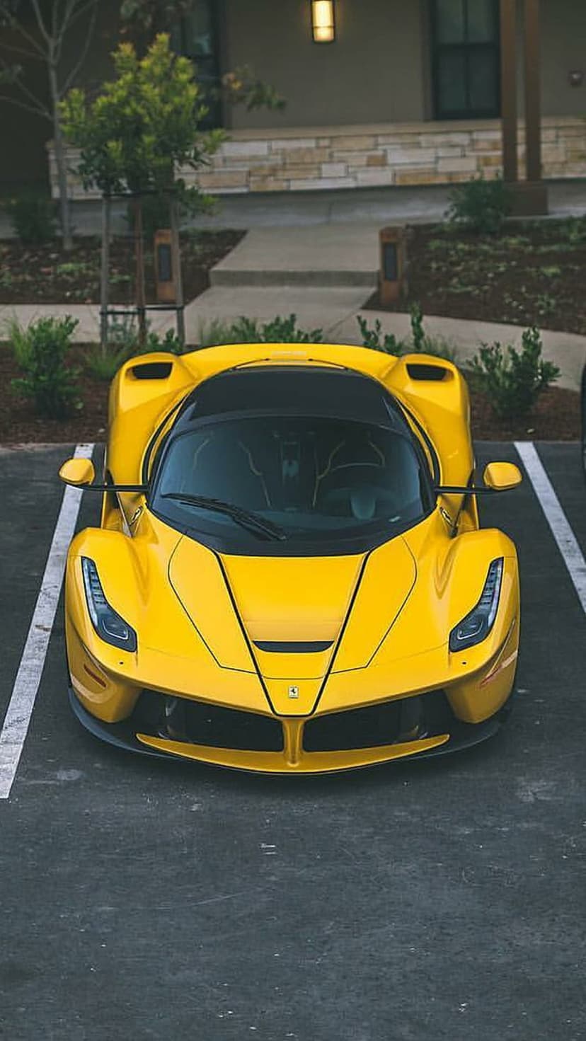 Yellow Ferrari LaFerrari parked on dark asphalt with a black roof and carbon fiber accents from a top-down view.